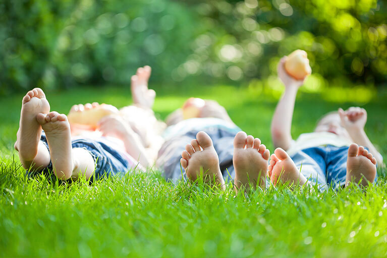 drei Kinder liegen auf einer Wiese